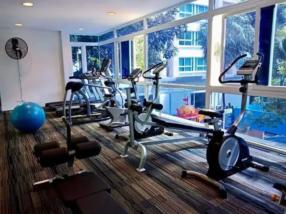 Modern fitness center with cardio equipment and views overlooking the pool
